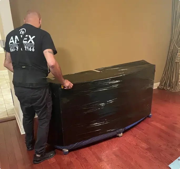 An AMEX mover in a branded shirt wrapping a piece of furniture